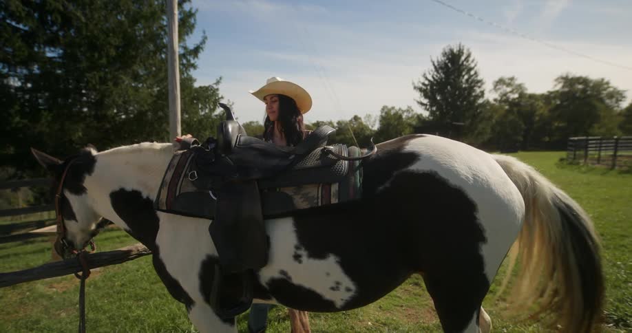 A lady preparing her horse for a ride