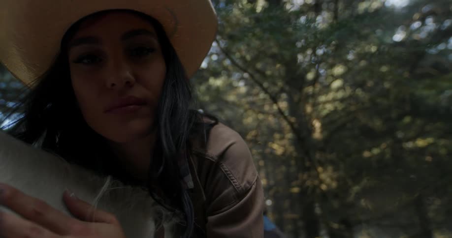 Woman wearing a cowboy hat riding a horse gently stroking and hugging it