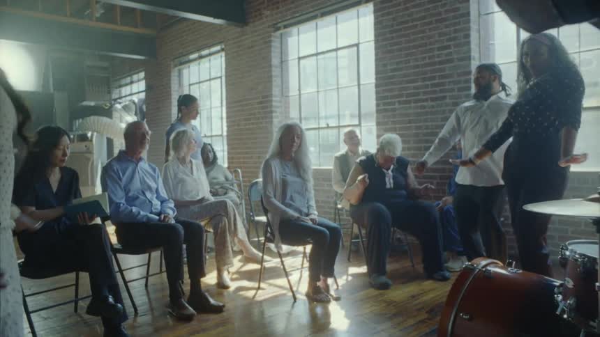 Musicians and dancers performing for a group of elderly people in a hall during the day