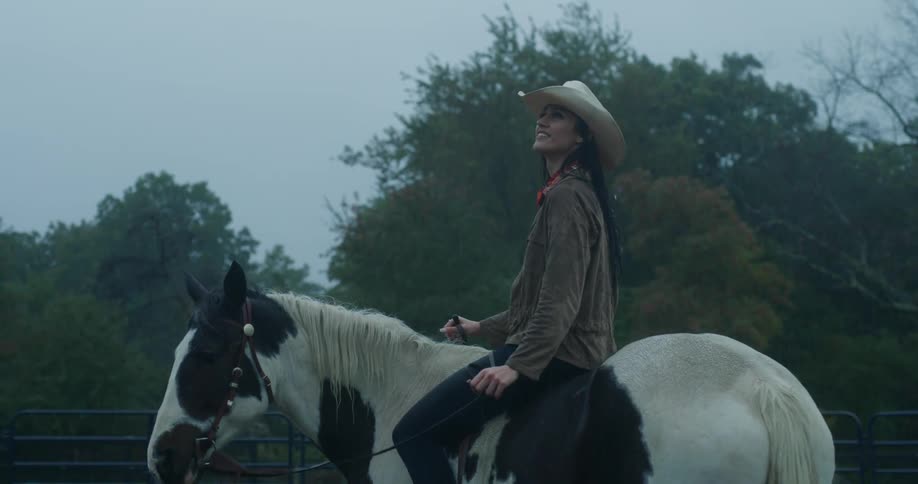 A woman riding a horse outdoors while it rains