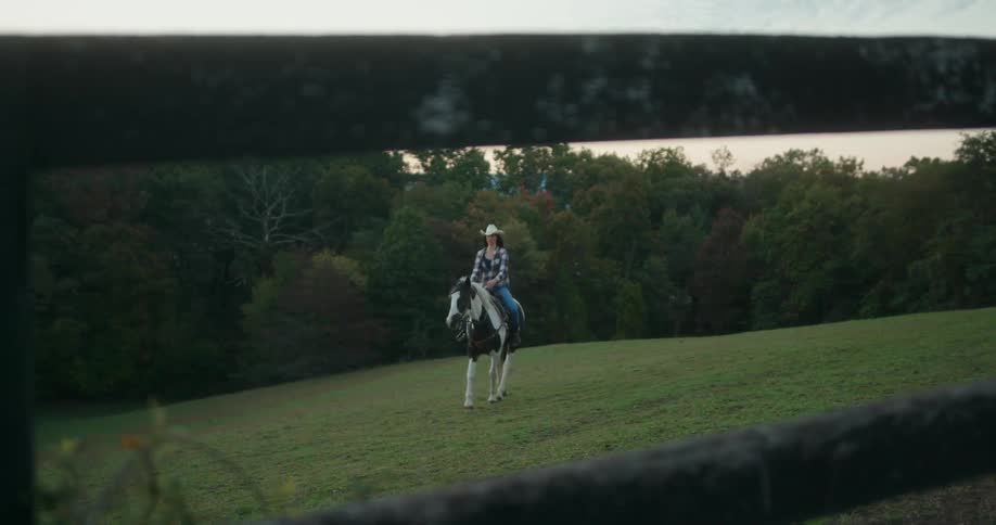 A woman rides her horse through the fence