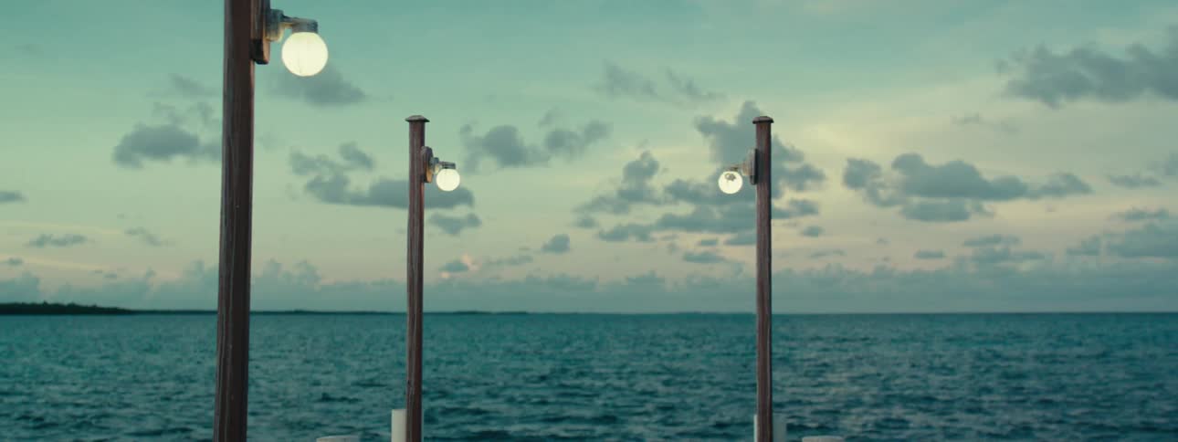 A wooden pier with streetlights lit during dusk