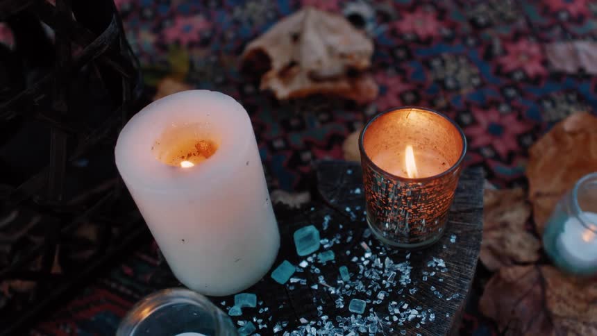 Flames flicker and burn within several candles that are arranged together