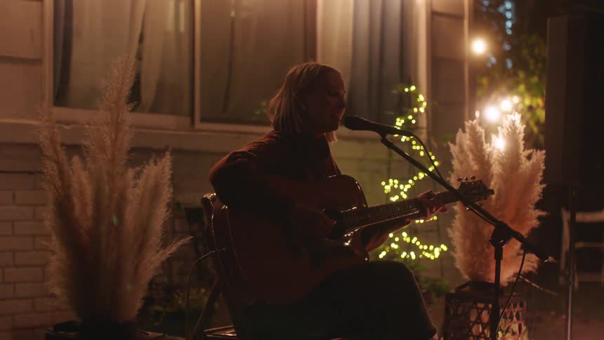 A woman singing in a garden lit at night