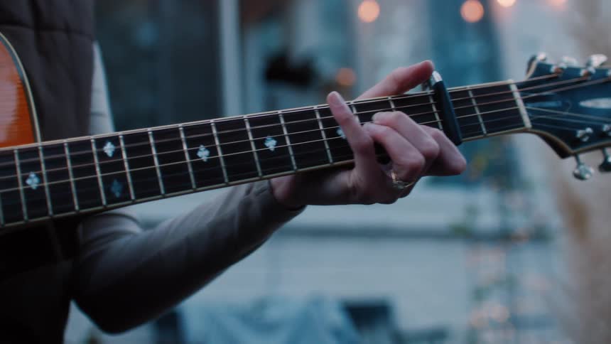 A woman sitting playing the guitar