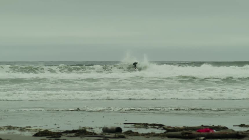 A man watches people surf by the shore