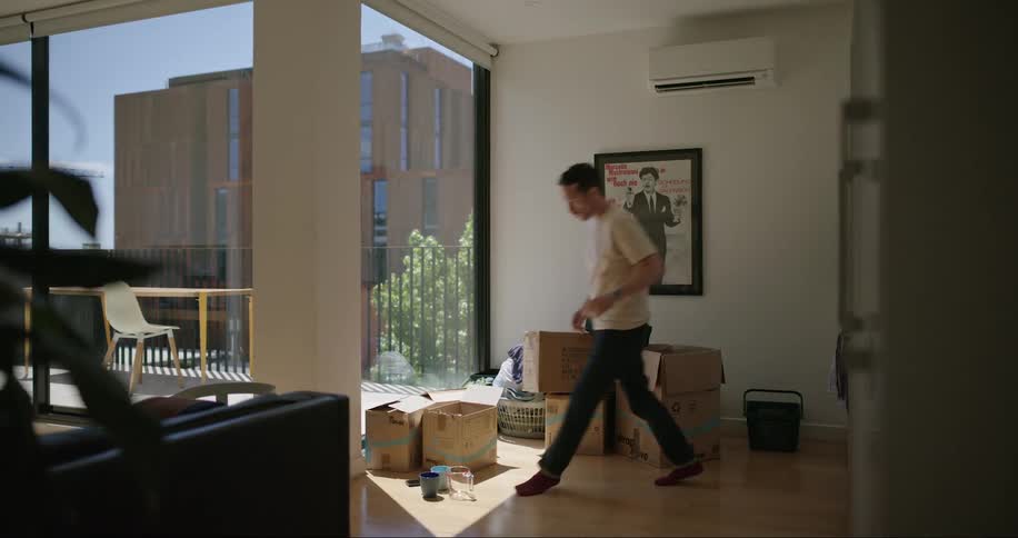 Man in his house picking up utensils that are on the floor and putting them away