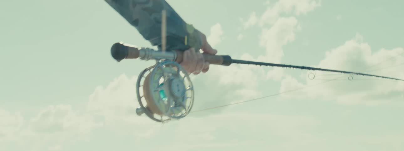 Closeup of a mans hands holding a fishing rod and releasing the line