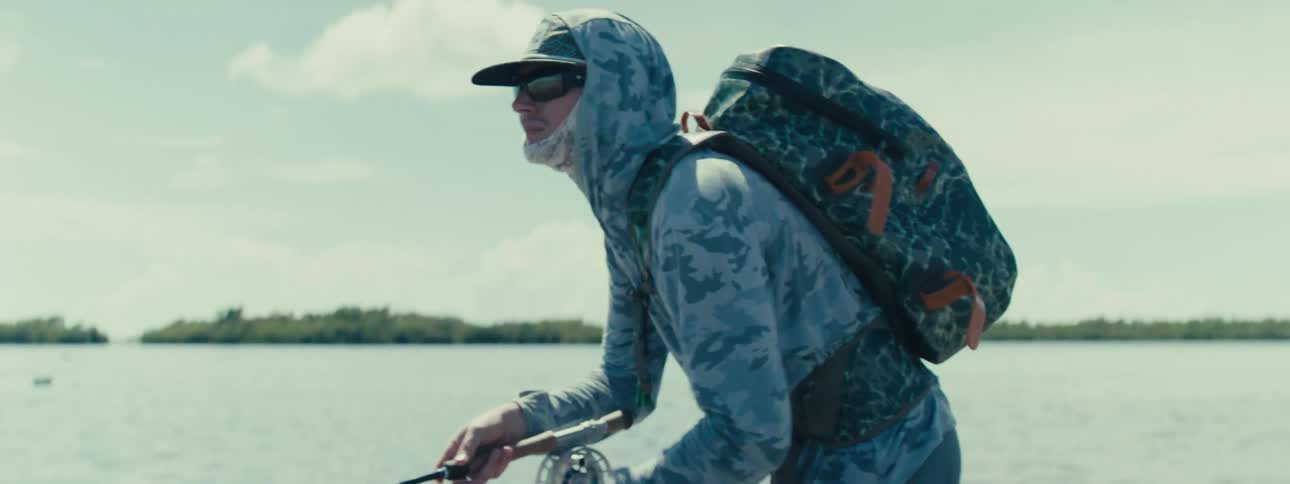 A man is fishing in the sea using a fishing rod and clothes