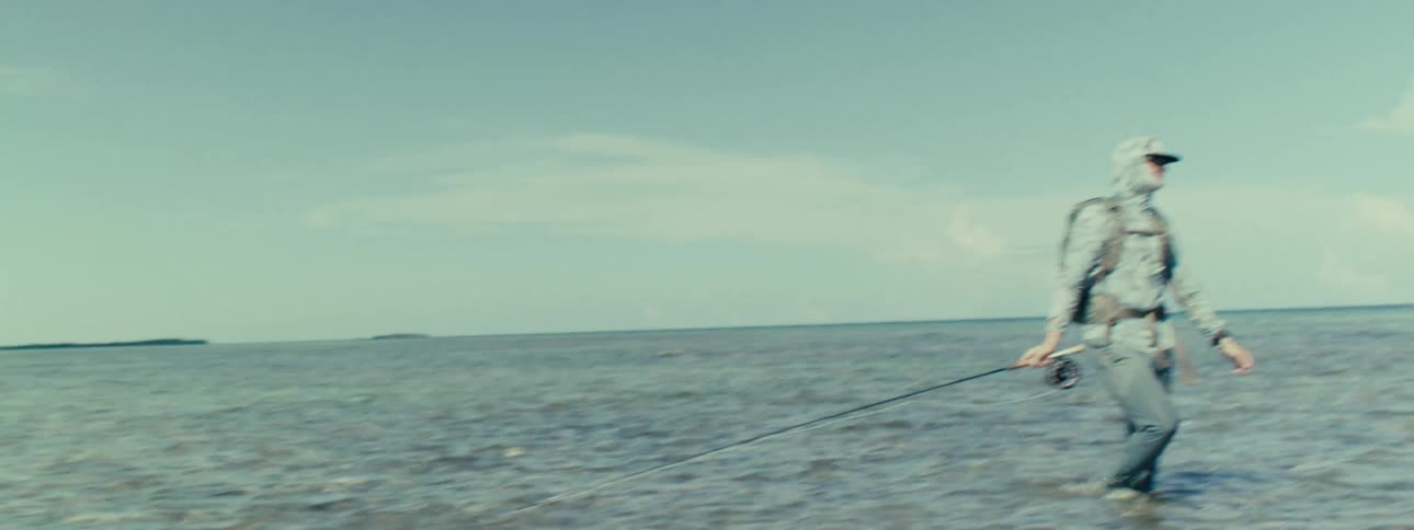 Two men are in the water fishing with rods
