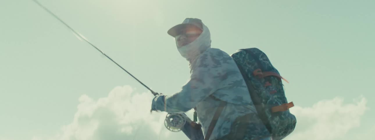 A man is in the water and fishing with a fishing rod