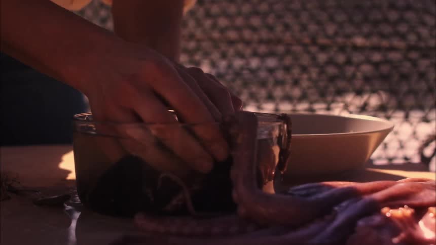 A person cleaning seafood in a pot of water