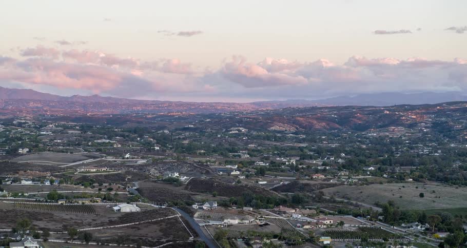 Aerial panorama of a residential neighborhood amidst fields under a morning sky