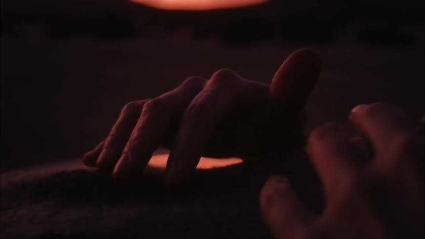 Woman runs her fingers over short haired fabric under a red tinted sky