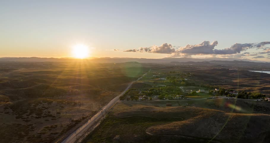 Aerial of moving cars on the road of a rural area at sunset