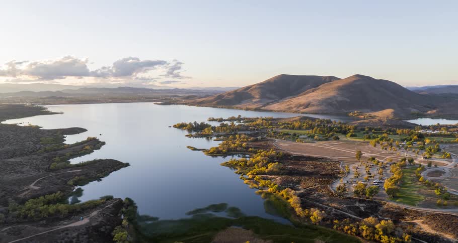 Aerial of lake surrounded by mountains and forest in the morning