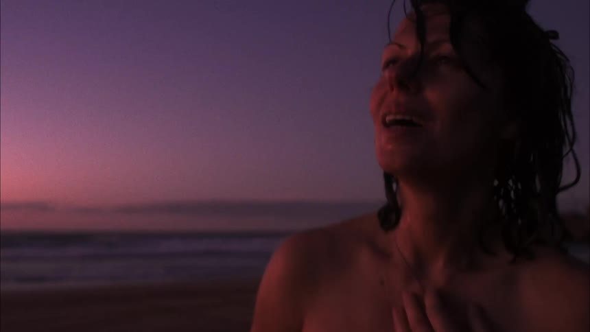 A tired woman walking by the beach side at sunset