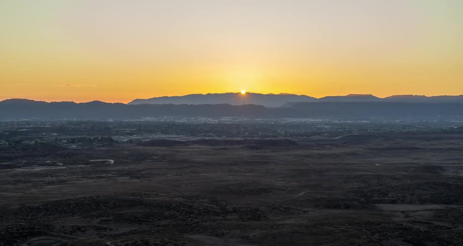 Aerial of the dry desert with the sun setting behind the mountains