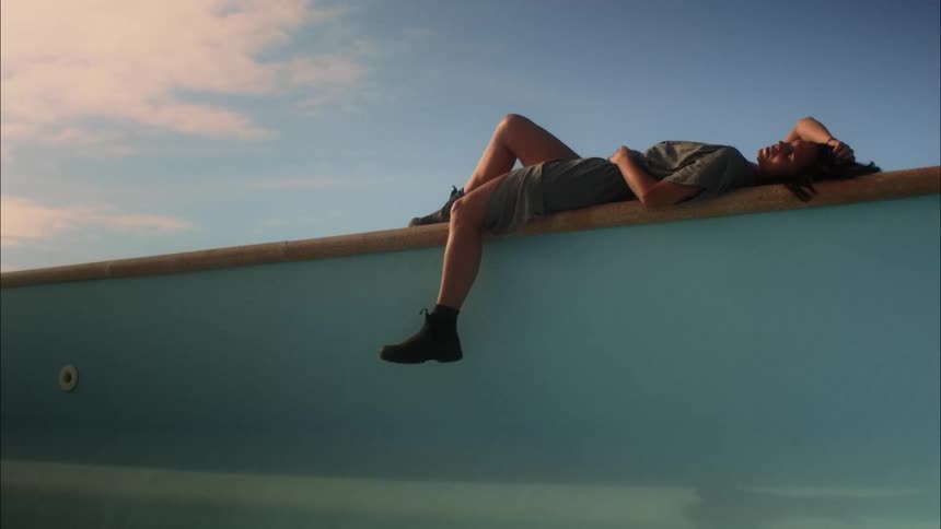 A woman lying on a wall watching the outdoor sky