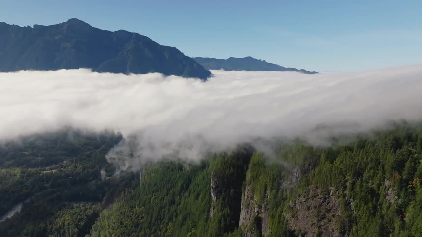 Panorama of a forest beneath mountains and cliffs at cloud level