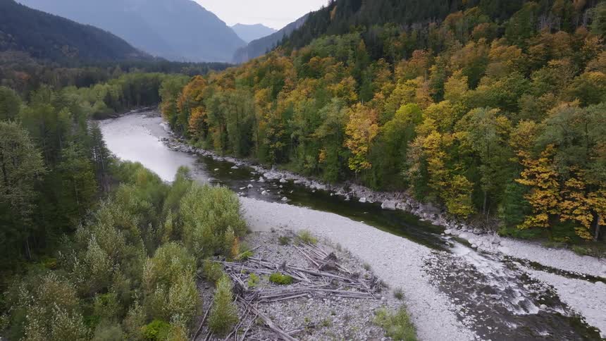 A small river flows through the canyon with autumnal forest on both sides