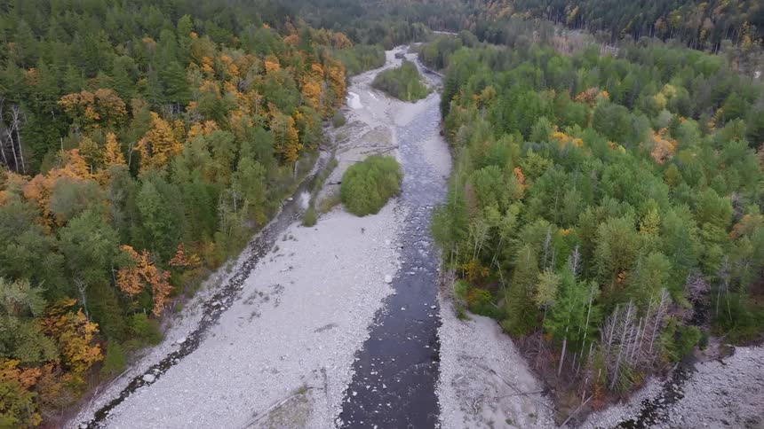 Aerial panorama of a semifrozen central river surrounded by forests