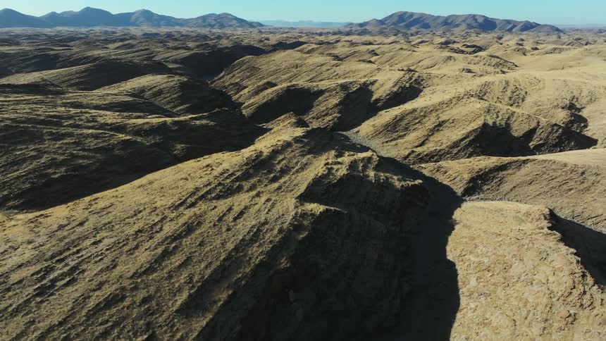 Aerial view of the rocky landscape with mountains in the background shows a barren and rugged wilderness