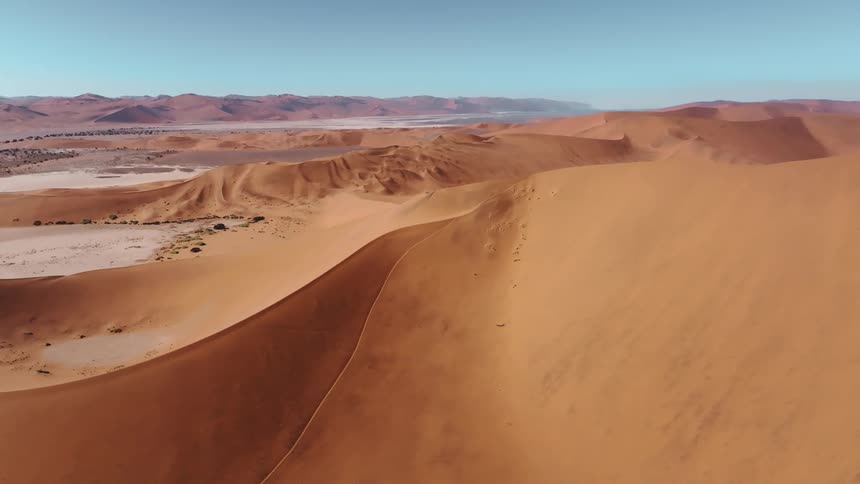 Vast sand dunes stretching across a desert under a clear sky during the day
