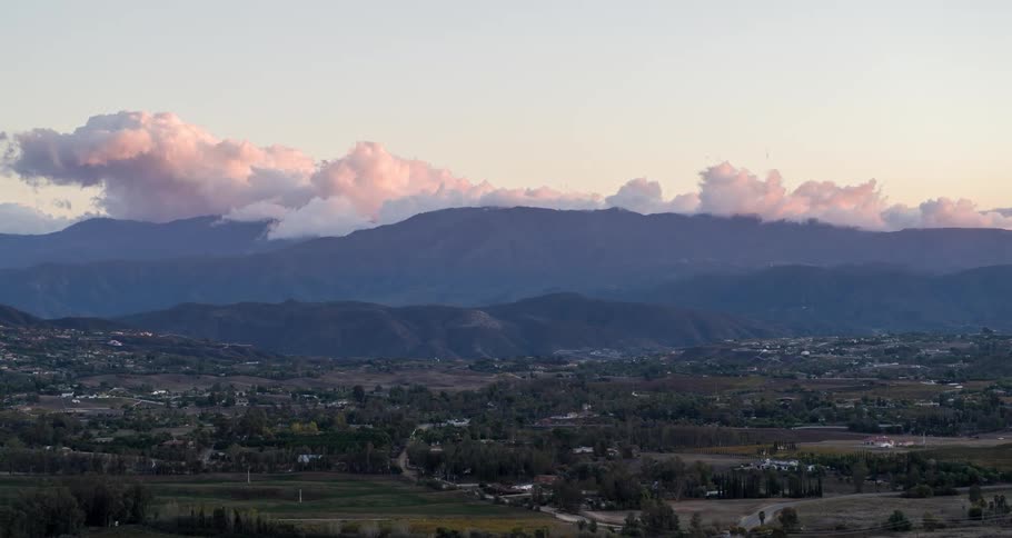 Aerial panorama of a city nestled amidst fields with a mountain range on the horizon on a morning