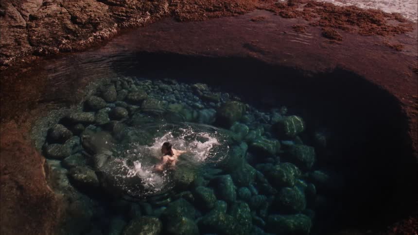 A person swimming in a lake with crystal clear water on a hot day