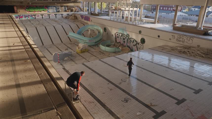 Two men walks in an empty swimming pool during the day
