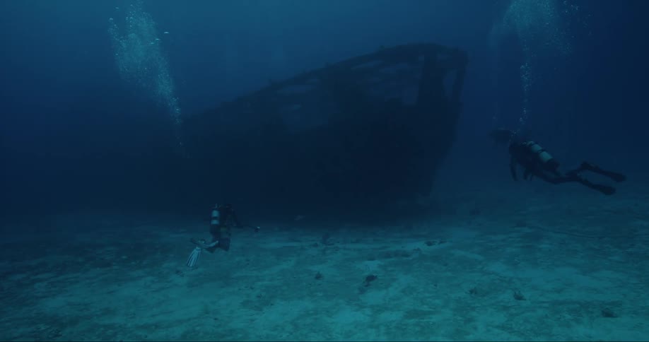 Divers and a sunken ship at the bottom of the ocean