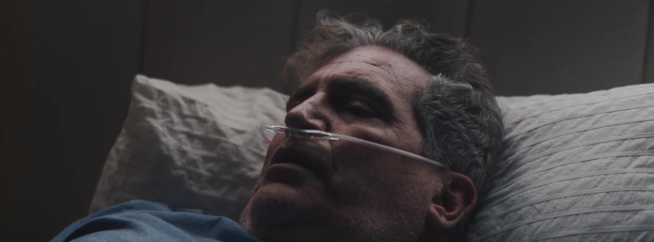 Senior man on oxygen wakes up and touches his head before sitting up