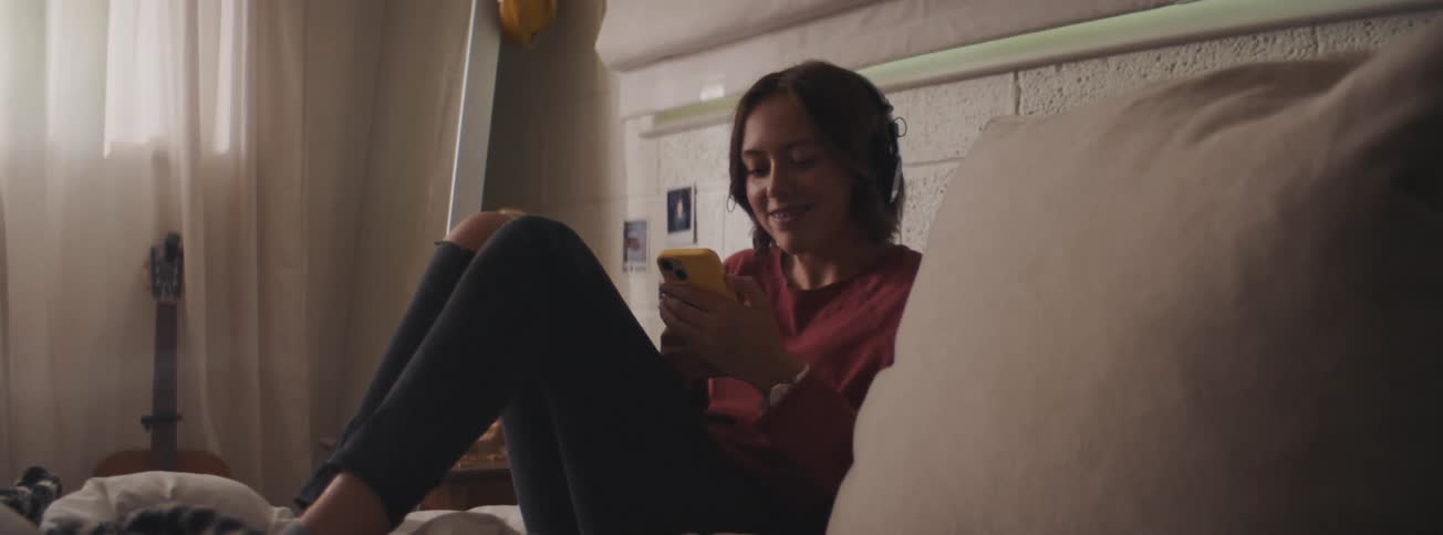 Woman sitting on the bed using her cellphone