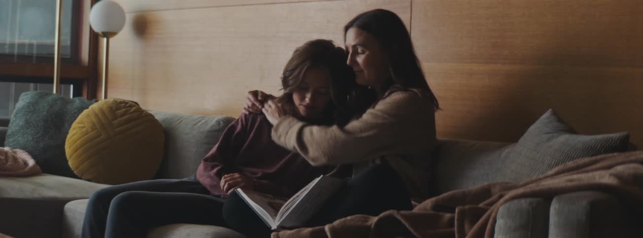 Mother and daughter sitting on the sofa hugging each other