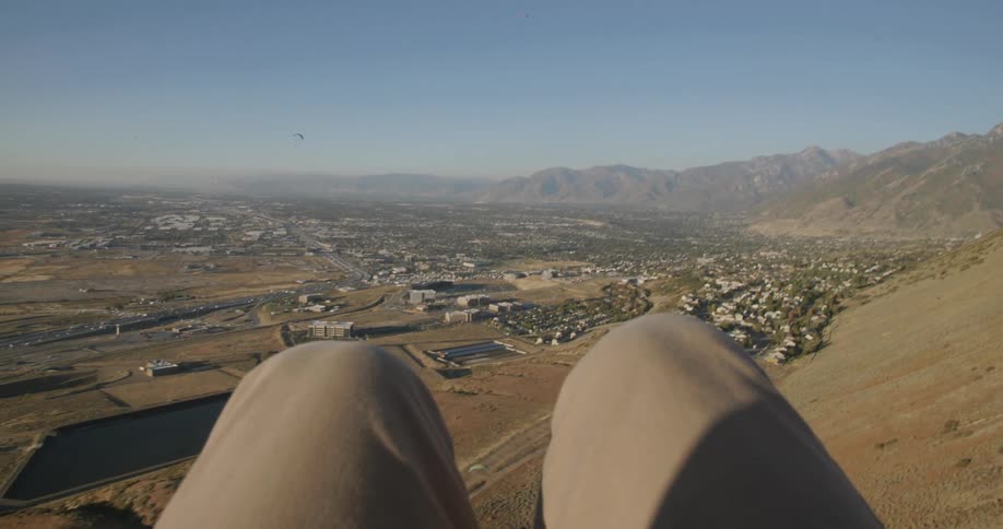 Person floats down on a parachute over the hills next to town