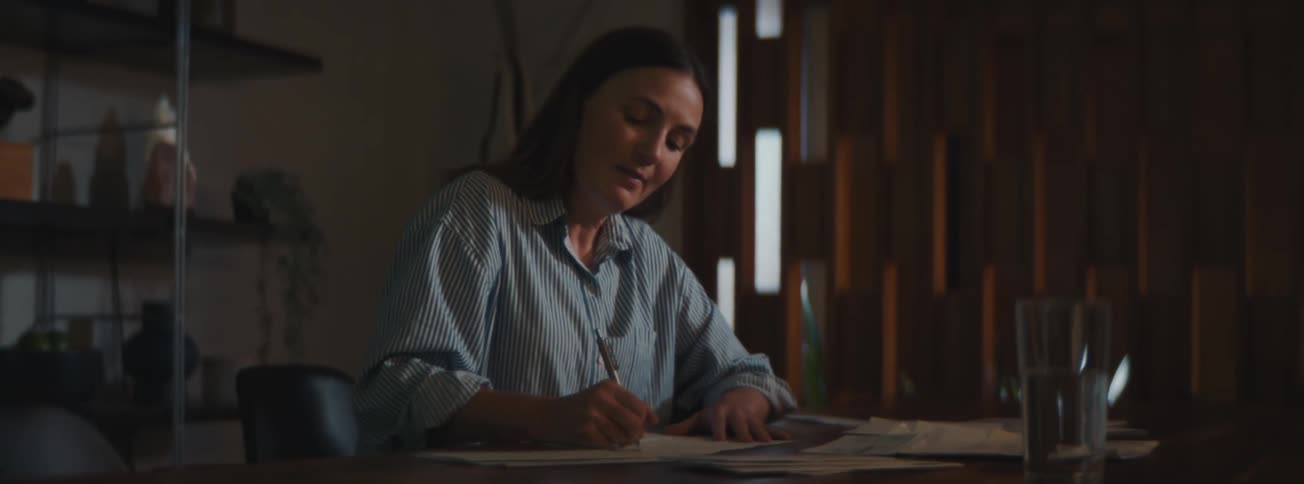 A woman signing a document at her work office