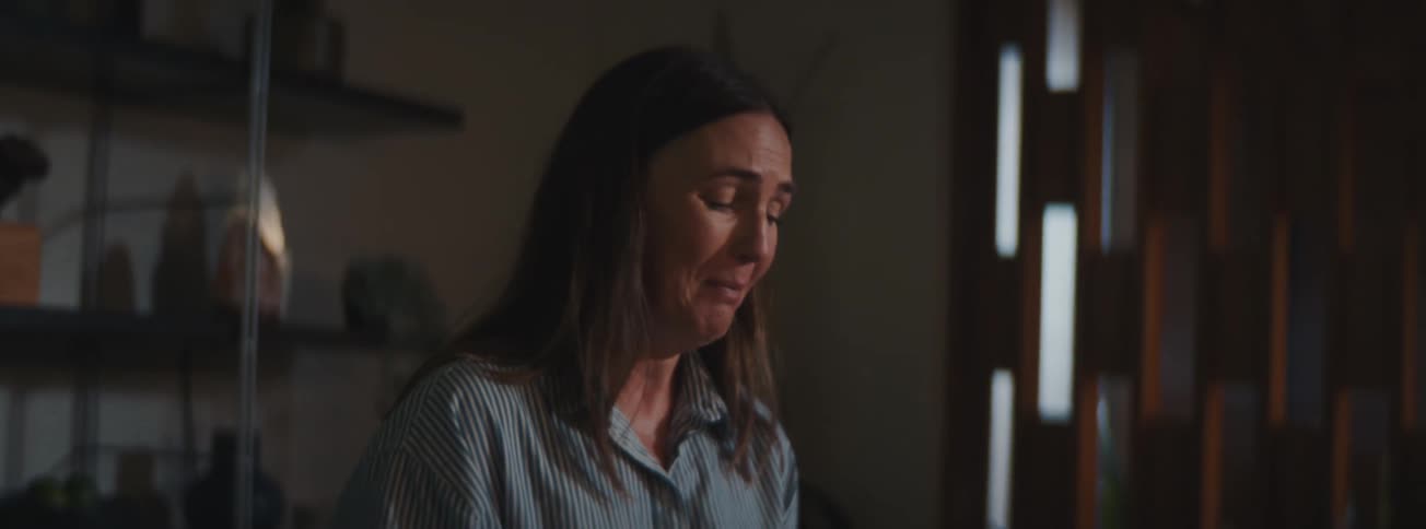 A woman seated in her dining room crying