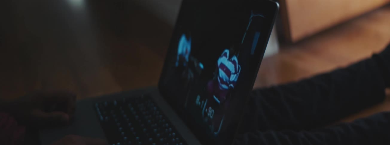 Man watching family movie on a laptop while seated on the floor indoor