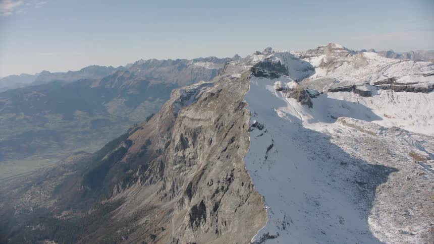 Aerial of white and brown rocky mountain peaks at sunrise