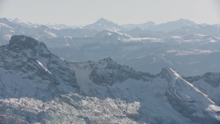 A mountain range partially covered in snow illuminated by the sun
