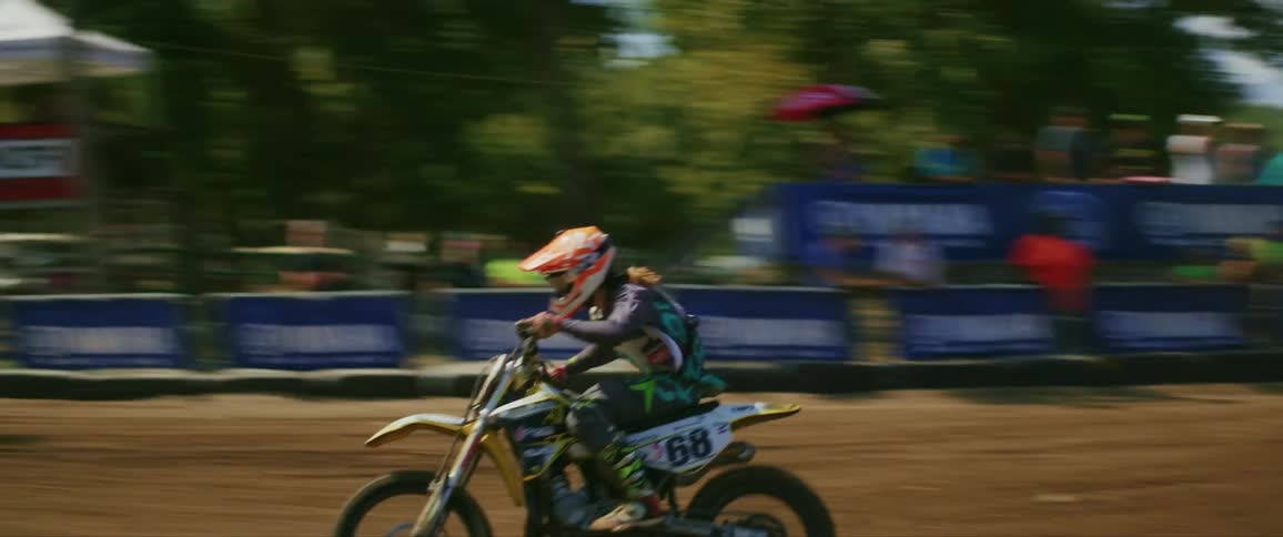 A person riding a motorcycle at high speed in a motocross competition