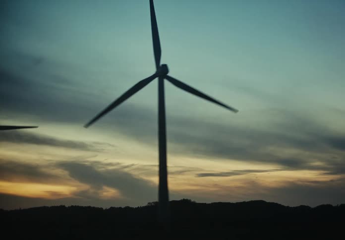 Wind turbines by the road side at sunset