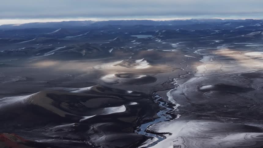 Aerial of a river in a black desert during a cloudy day