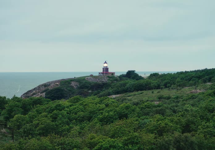Light beaming as it spins inside the dome top of a lighthouse on the top of a green hillside