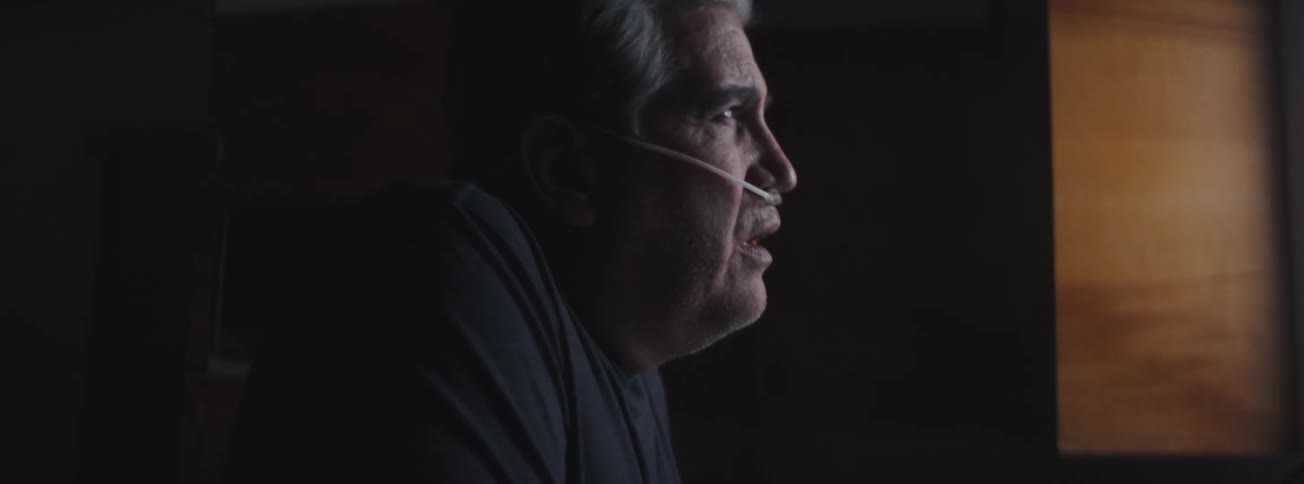 Senior man looking out of the window taking a deep breath and with a catheter in the nose