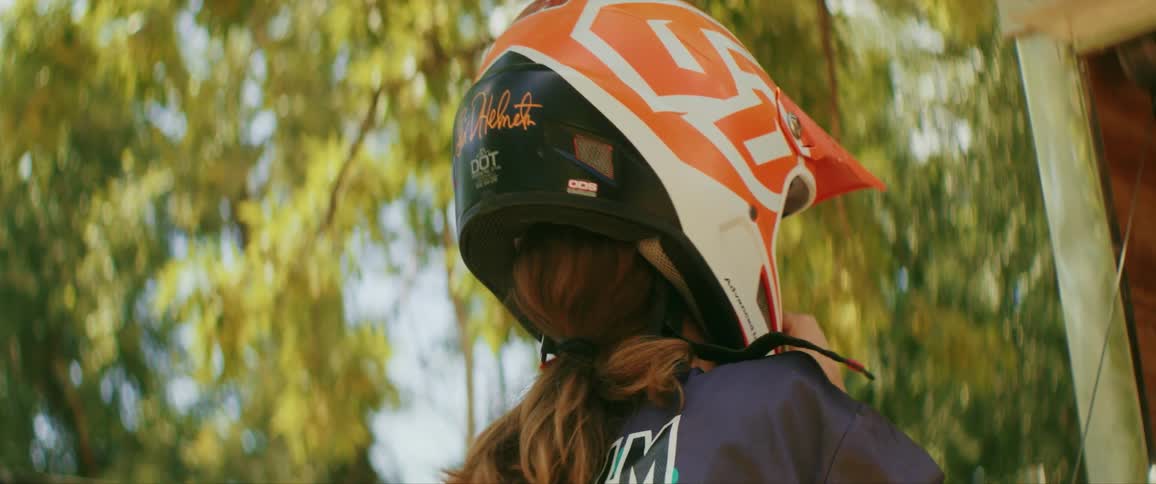 A female fixes the helmet on her head during the day