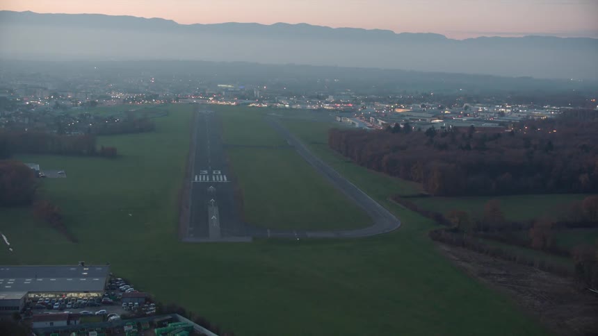 An airport runway near residential areas and forest trees