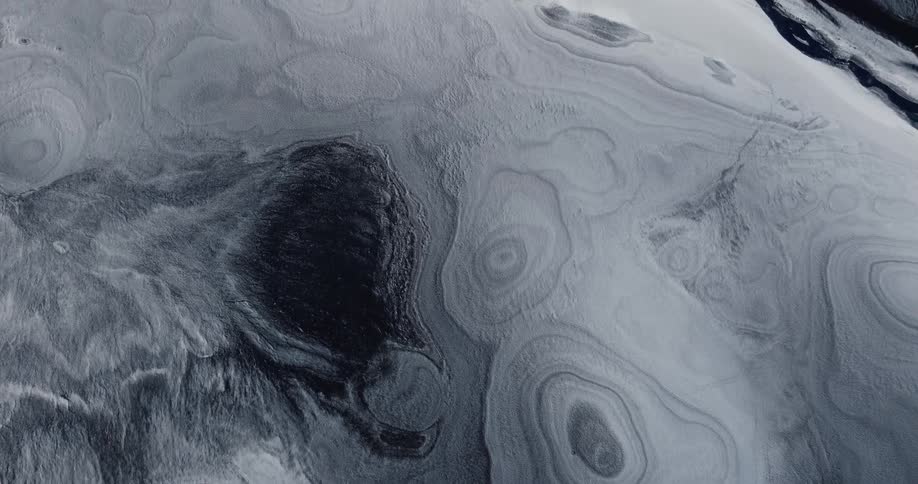 An aerial view of an icy terrain with different patches of snow