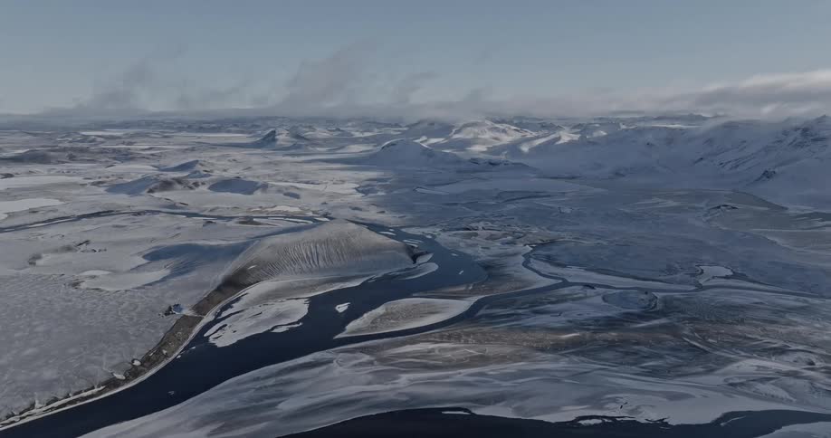 Aerial of mountains with snow and frozen river during winter